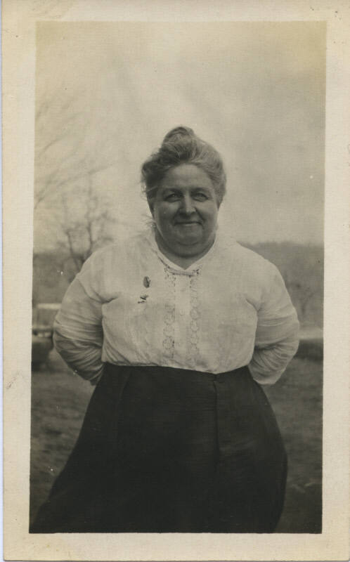Untitled [Woman stands on field, hands behind back]