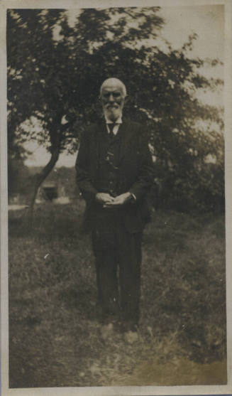 Untitled [Man stands in field, hands in front]