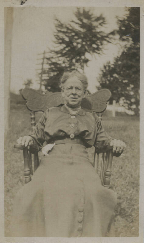 Untitled [Woman sits on chair, in lawn]