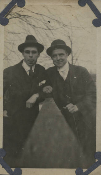 Untitled [Two men stand side by side, fence in between]