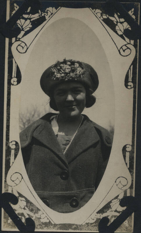 Untitled [Woman wears coat and hat with flowers]