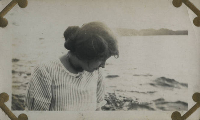 Untitled [Woman looks down, body of water in background]