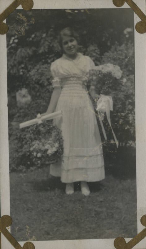 Untitled [Woman stands in garden, holds flowers]