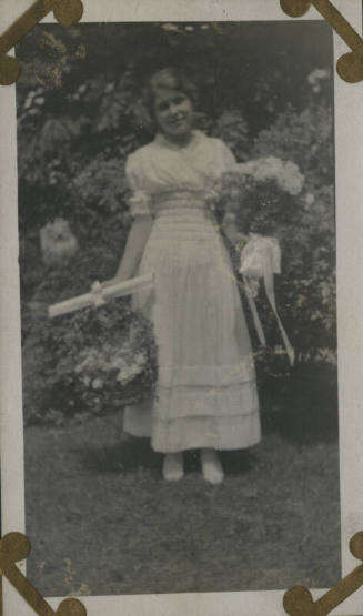 Untitled [Woman stands in garden, holds flowers]