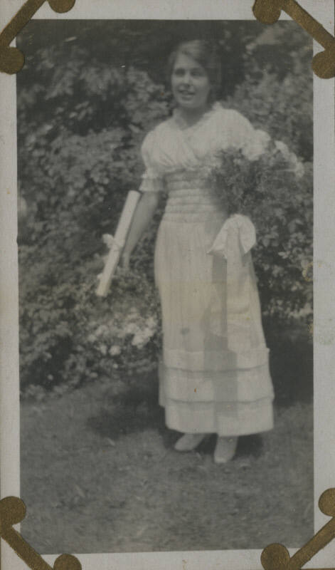 Untitled [Woman stands in garden, holds flowers]