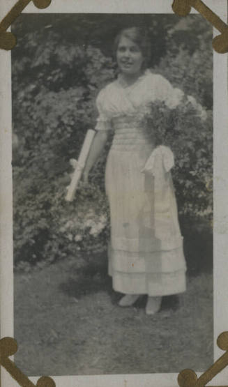 Untitled [Woman stands in garden, holds flowers]