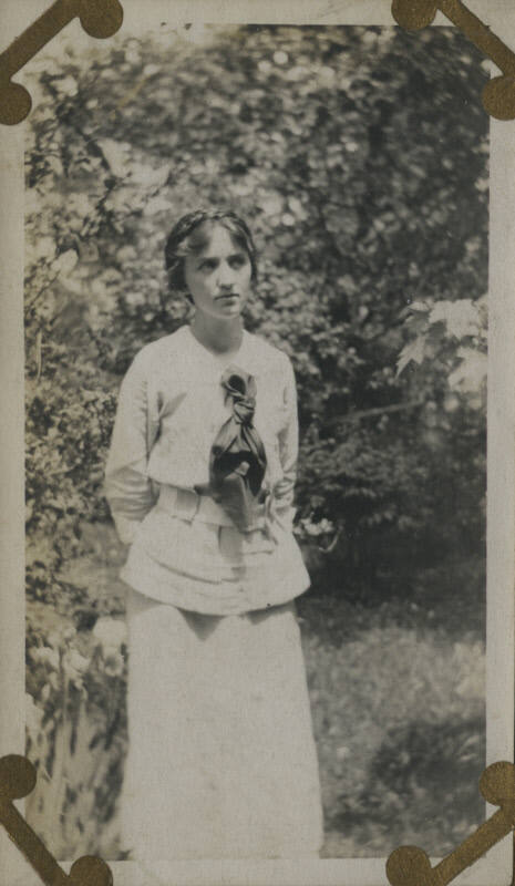 Untitled [Woman stands in forest, hands behind back]