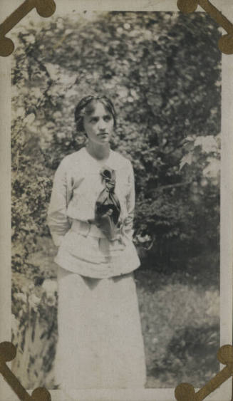 Untitled [Woman stands in forest, hands behind back]