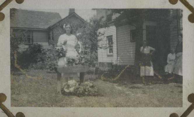 Untitled [Woman stands outside, flowers in front of her]