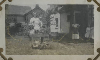 Untitled [Woman stands outside, flowers in front of her]