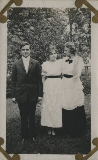 Untitled [Two women and a man stand on lawn]