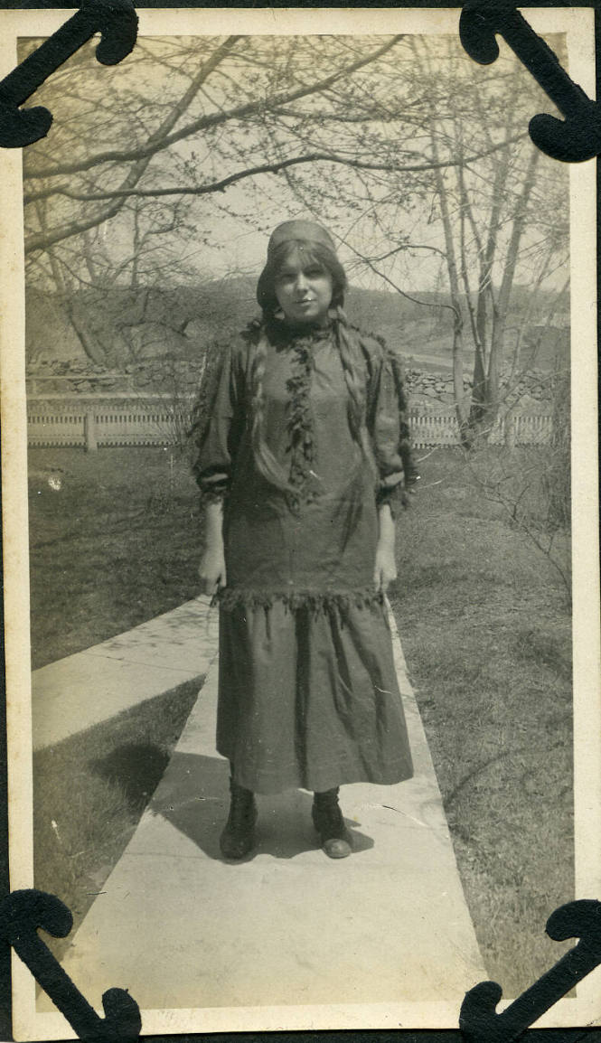 Untitled [Woman stands on concrete path, trees and hills in background]