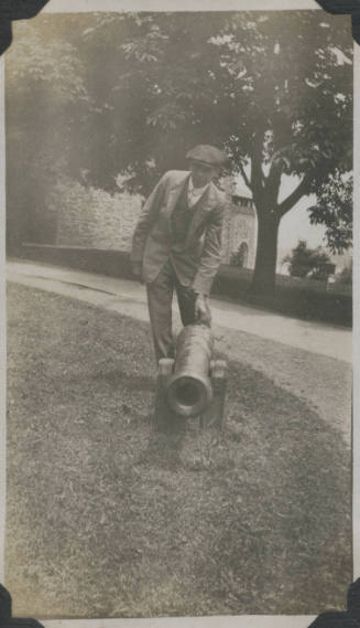Untitled [Man leans down to touch cannon]