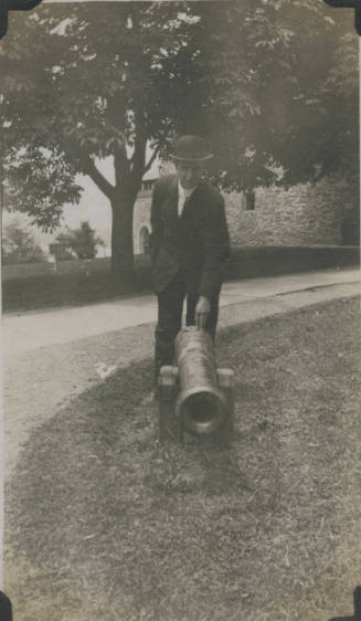 Untitled [Man leans down to touch cannon]