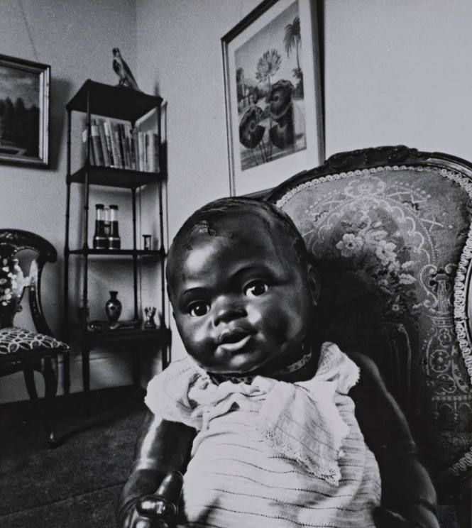 Black Doll Sitting in Room