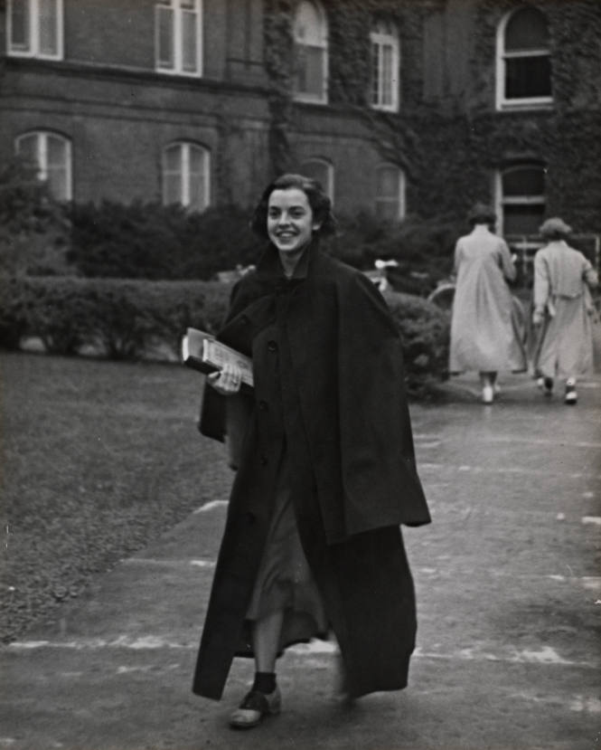 Smiling student crossing campus from Main to Rockefeller, Vassar College
