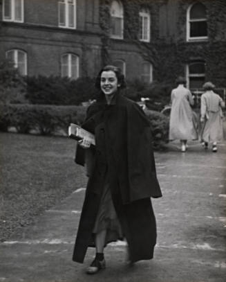 Smiling student crossing campus from Main to Rockefeller, Vassar College