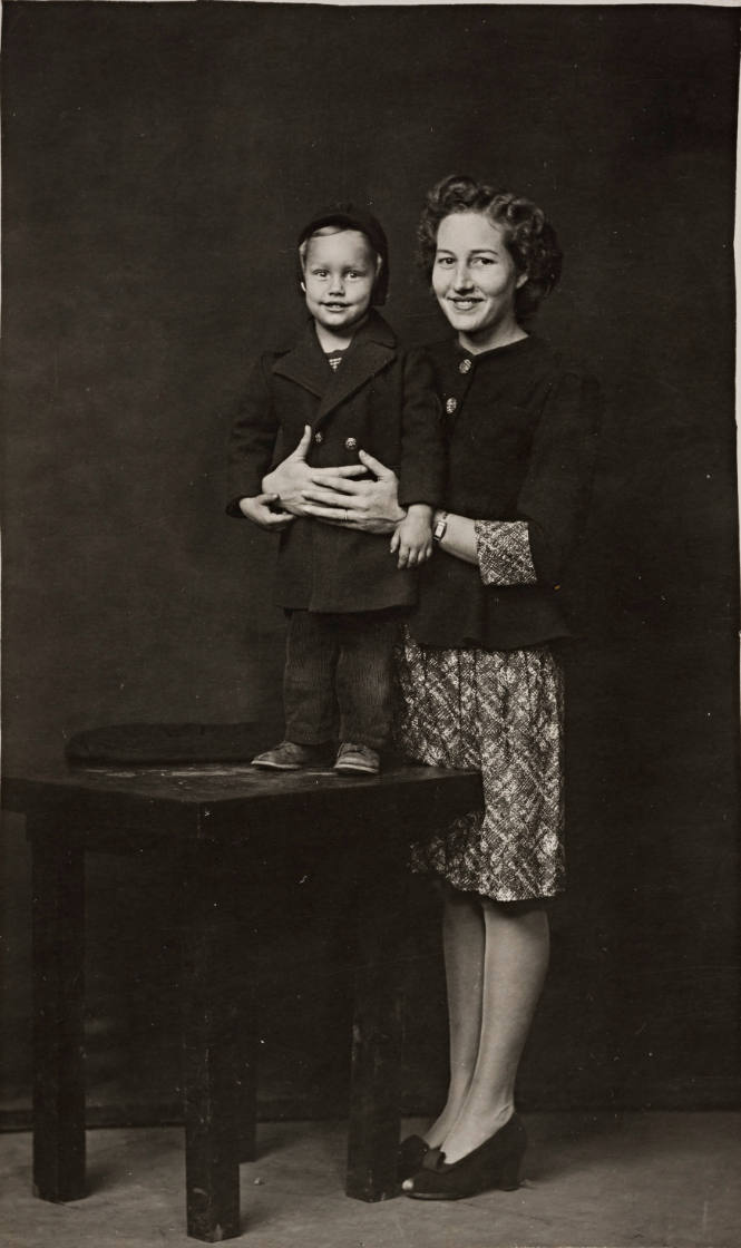 Woman with arms around child on table, both wearing coats