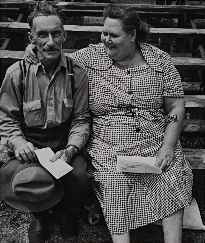 Man and woman embracing him sitting on stands, US