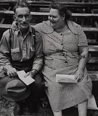 Man and woman embracing him sitting on stands, US