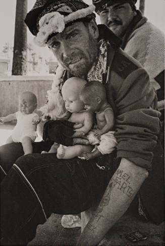 Man holding three dolls, Venice Beach, California