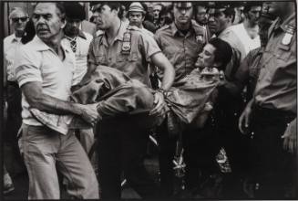 Subdued, the man is carried away in a straightjacket