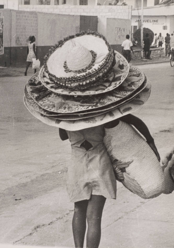 Woman walking, wearing multiple hats, seen from behind