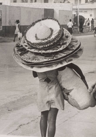 Woman walking, wearing multiple hats, seen from behind