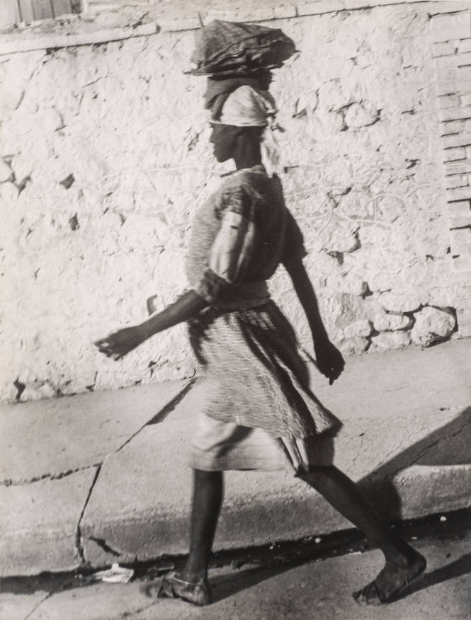 Woman walking carrying package on head