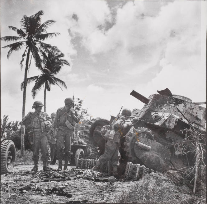 Wrecked Japanese tank inspected by troops moving inland, Philippines