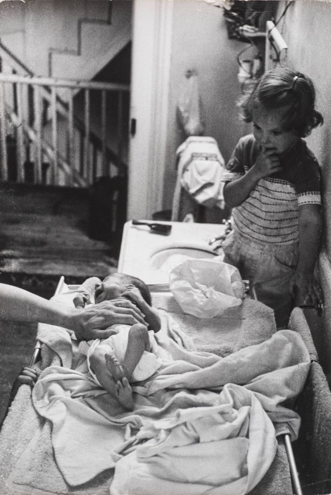 Newborn crying on changing table while sister watches