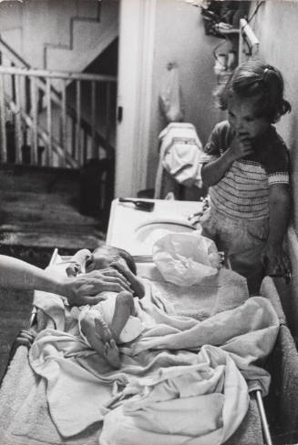 Newborn crying on changing table while sister watches