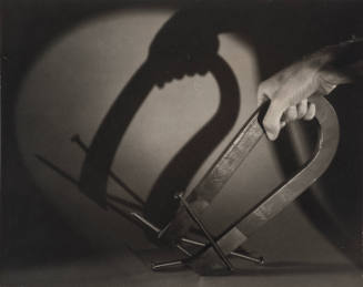 Still life with hand holding horseshoe magnet with nails attached