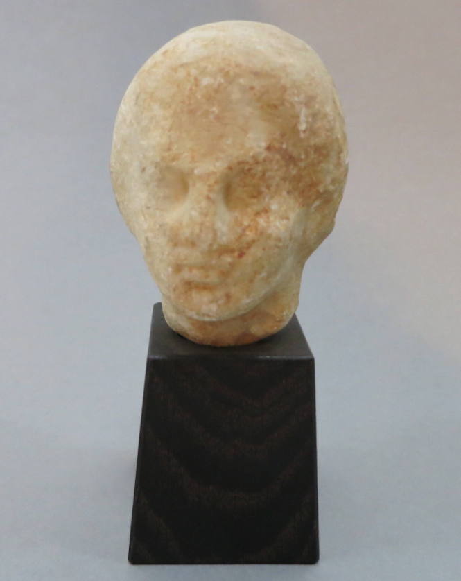 Fragmentary head of youth; head turned to left; weathered