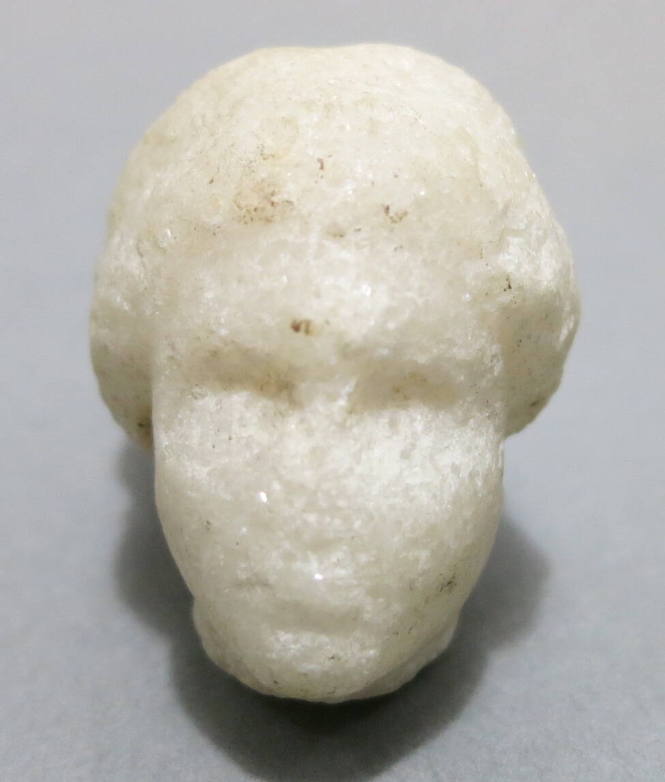 Miniature head (of Aphrodite?), her hair bound in large chignon, with drill holes for earrings