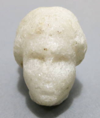 Miniature head (of Aphrodite?), her hair bound in large chignon, with drill holes for earrings