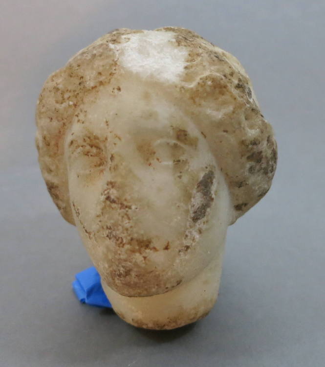 Head of a woman with rolled coiffure, headband, chignon at nape of neck
