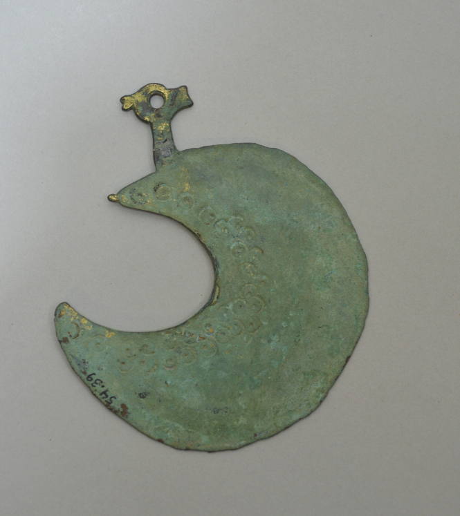 Lunate razor with stamped circles and Christian symbol incised on back, and bird's head attachment