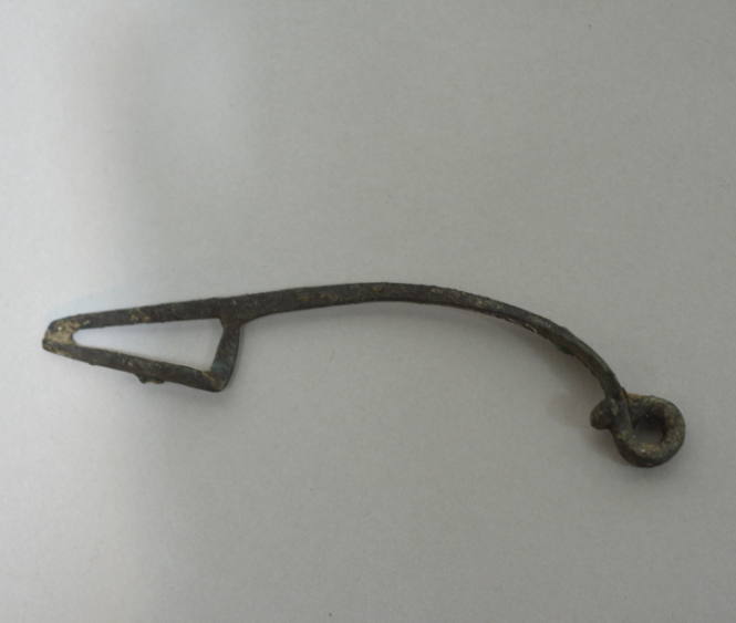 Fibula of elongated shape, with flattened bow, quapruple spiral spring, and perforated catch