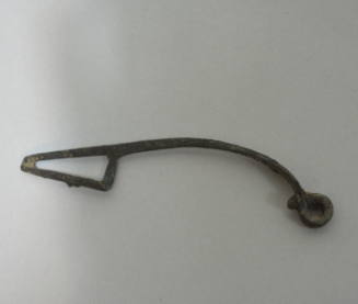 Fibula of elongated shape, with flattened bow, quapruple spiral spring, and perforated catch