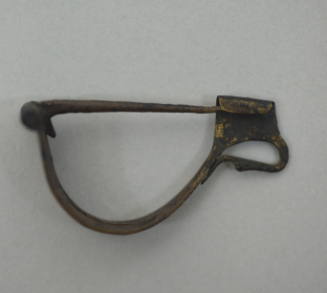Fibula with simple bow, perforated, decorated with longitudinal rope pattern