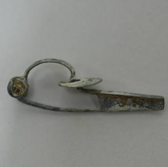 Fibula with six spiral spring, bow and tongue of flattened bronze, flat disc threaded on bow and catch with two perforations