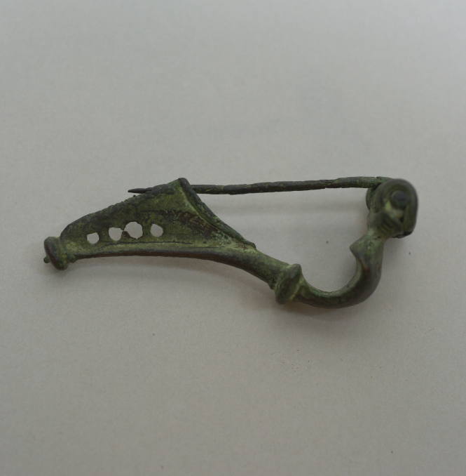 Fibula of Certosa-type, with eight spirals at spring, and knob at end of catch; catch perforated with four holes