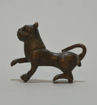 Figurine of a lion, with tail curved up over the haunches, and the right paw lifted