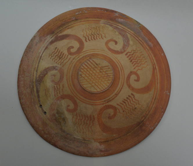 Italic plate; pinted with spirals and wavy lines on exterior, encircling bands on interior; two holes in rim for suspension