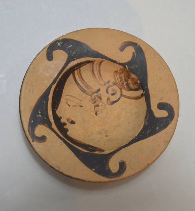 Etruscan pedestal dish, the interior painted with a profile head within a spiral hook border