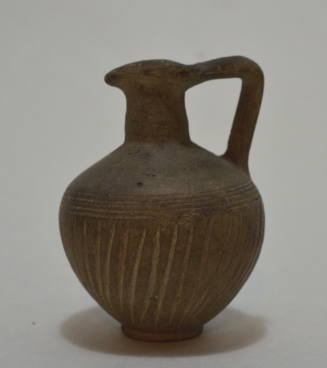 Greyware jug with round base and pinched spout and incised decoration and five incised rings around body