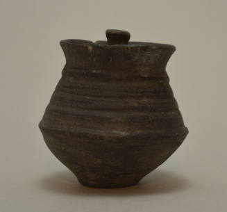Greyish black vase with angular profiled body, wide mouth, and horizontal ridges on body