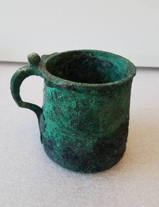 Cup of tapering cylindrical form, with looped hadle and encircling incisions