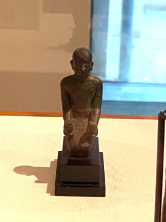 Kneeling priest holding nu-pots in his extended hands